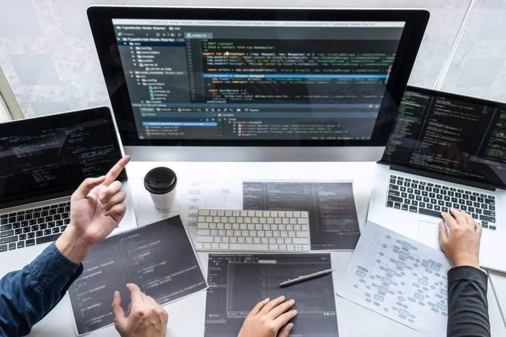 Image with three laptops and code on their screens